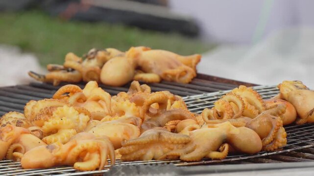 Grilled squid pieces cooking on a barbecue rack
