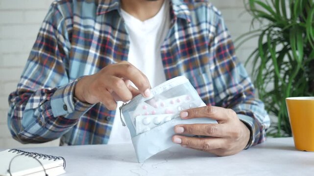 Person taking out medicine blister pack from small travel pouch at desk