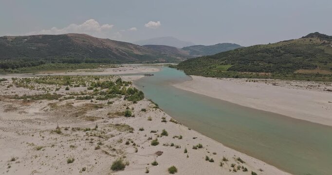 Vjosa River Albania Aerial v1 low flyover wild river capturing turquoise waters flowing through a valley with sandy banks and mountains in the background - Shot with 5k Camera - July 12th 2024