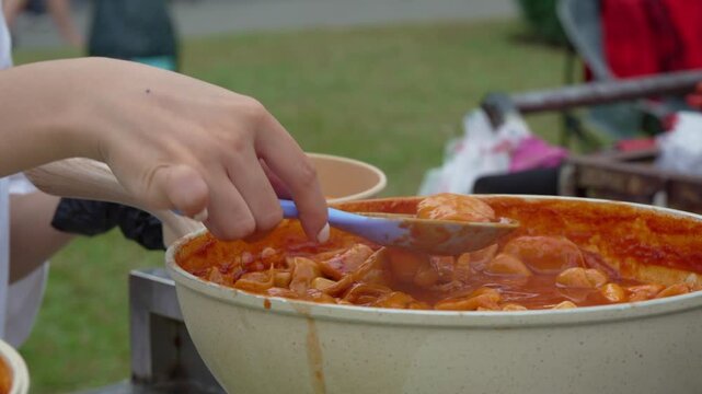 Savory red sauce simmering in a large pot at a food stall