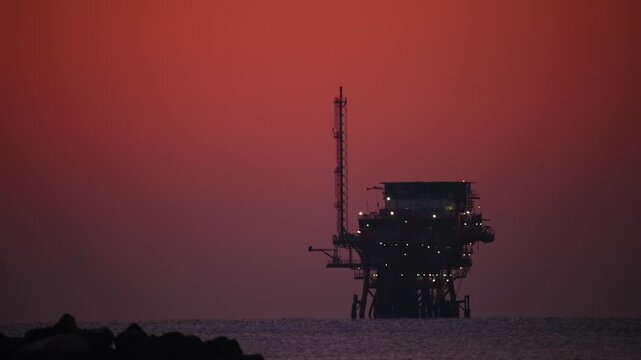 Oil rig silhouette against a sunset sky