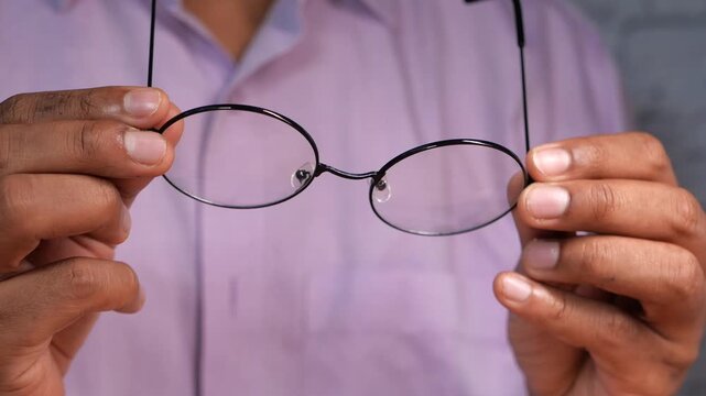 Close up view of man wearing light purple shirt showing round black frame glasses with clear lenses looking at camera