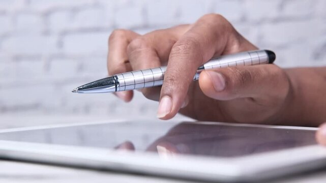 Person using finger and stylus on digital tablet screen for design work in office environment