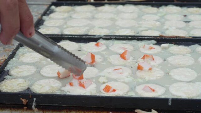 White round street food snacks cooking in a griddle pan
