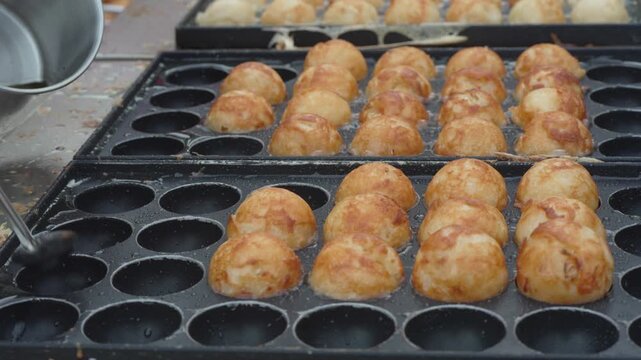 Fresh golden round snacks cooking in a street food griddle