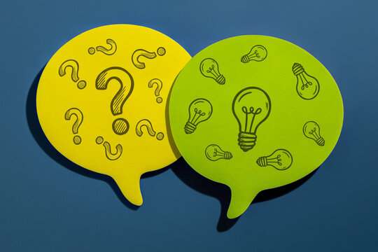 Yellow and green speech bubble notes with drawn question marks and lightbulbs. Brainstorming, problem-solving, FAQ, ideation, solutions concept.