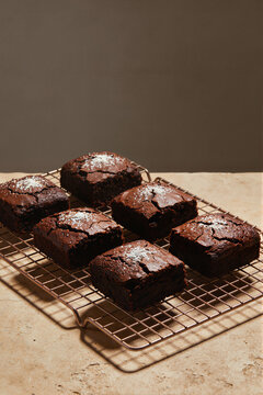 Dark chocolate brownies dusted with powdered sugar on metal cooling rack