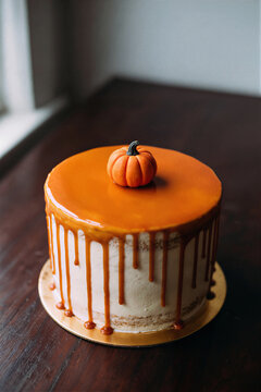 Round cake with glossy burnt orange drip glaze and miniature pumpkin top