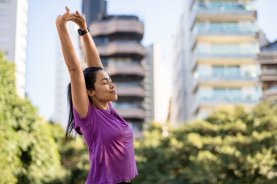 Woman, stretching and smiling in city with fitness, morning routine or wellness outdoor. Athlete or person with arms overhead, smart watch and workout warm up in park