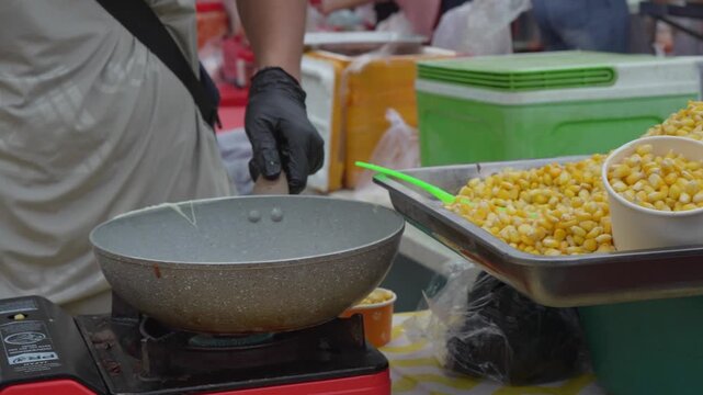 Vendor stirring a savory mixture in a large wok at a street market