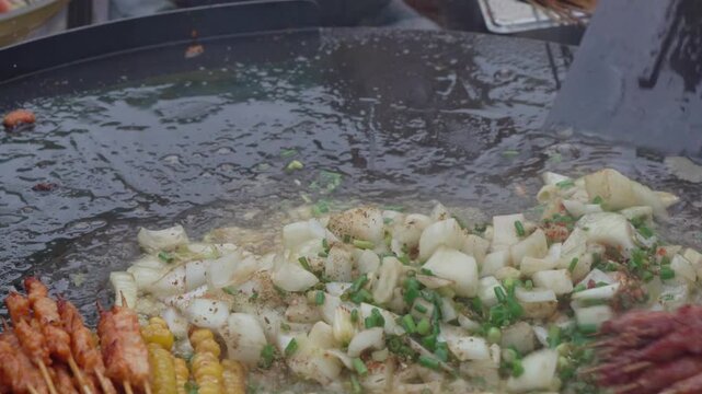 Grilled mixed street food cooking on a flat barbecue grill