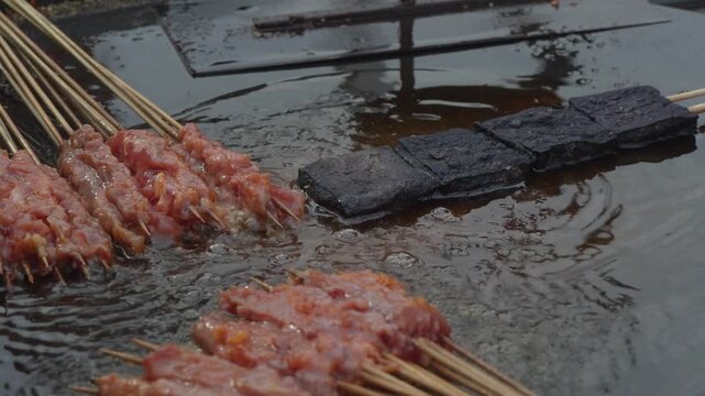 Raw sausage skewers prepared for grilling at a street food market