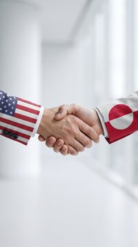Close up of business handshake between representatives wearing suit jackets patterned after United States and Greenland national flags symbol of bilateral partnership