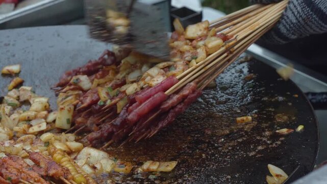 Red meat and sausage skewers cooking on a street food grill