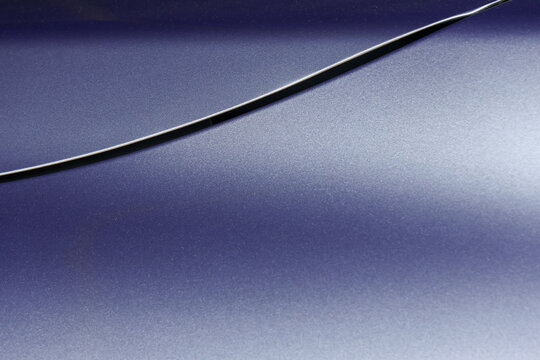 Abstract metallic surface with curved black line and soft blue gradient creating sleek modern background with dramatic contrast and elegant visual tension