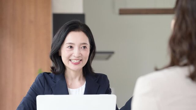 笑顔で説明する50代の日本人女性ビジネスパーソン、住宅のローン金利見直しのファイナンシャルプランナや、顧客との商談や提案、面談でコミュニケーションする管理職のイメージの動画