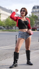 Young Asian woman wearing a red cropped cardigan, black tank top, and black boots stands on a Parisian street © iFocus
