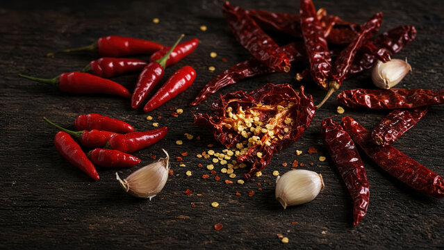 Scattered Red Chilies Spilling Seeds on Dark Wood