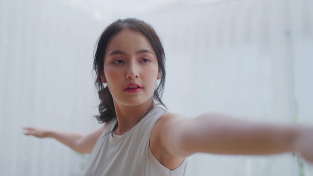 Happy young Asian woman practicing yoga and shoulder stretching  in living room at home
