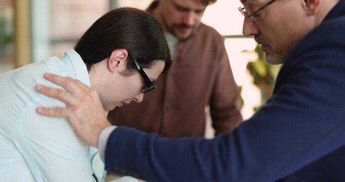 Close up middle aged psychologist consoling supporting female patient during group therapy holding hand on her shoulder helping cope with grief mental health problems on rehabilitation program meeting