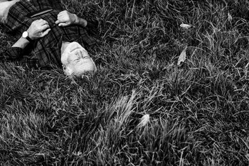Obraz premium Elderly man relaxing on grass in black and white photo