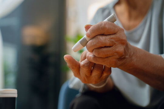 Elderly woman using a lancet for blood sugar testing at home, diabetes care and glucose monitoring.