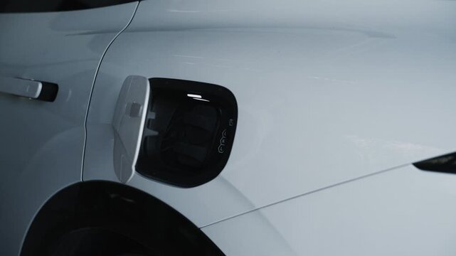 Close-up of open charging port door on modern white electric vehicle car
