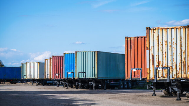 Colorful freight containers on semi-trailers parked in a parking lot.