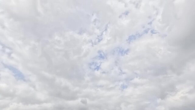 Low angle video footage of white overcast clouds moving across bright blue sky. Natural atmospheric skyscape timelapse background template for weather forecast, nature video, and wallpaper.