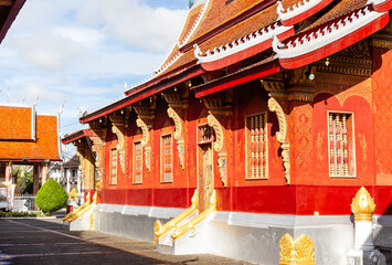 Ornate red and gold temple structure with traditional multi-tiered roof at Wat Sibounheuang in Luang Prabang, Laos. © Eugene Ga