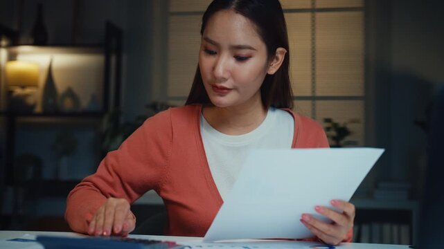 Young Asian woman calculates bills and household expenses with calculator and laptop at home at night. Personal finance budgeting, tax payment plan, debt control, savings mortgage management concept.