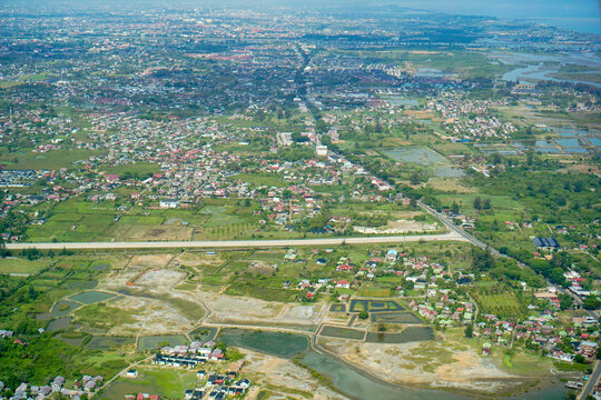 Banda Aceh and Aceh Besar aerial view from above. Aerial view of Aceh Besar landscape, including residential areas, green fields, and a new toll road under construction. Looking towards the ocean.