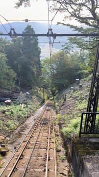 Mountain funicular railway track climbing through forest Japan