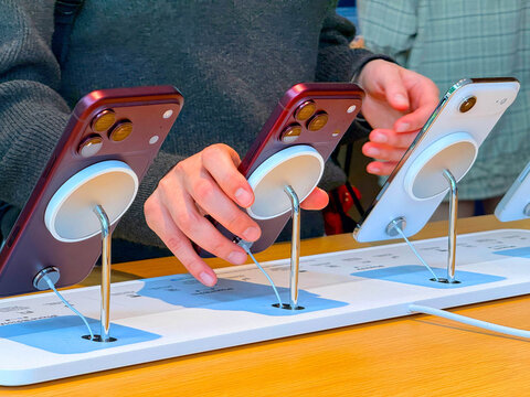 BANGKOK, THAILAND - SEPTEMBER 19, 2026: Customers testing new Burgundy iPhone 18 Pro Max models on MagSafe charging stands inside Apple Store Central World.