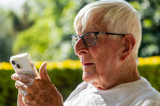 close up profile of elderly man looking at smart phone at sunset