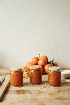 Three jars of homemade Seville orange marmalade cooling on a scrubbed pine table