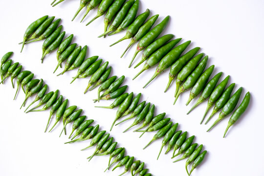 Pattern of fresh green bird's eye chilies or cabe rawit hijau arranged in a grid on white background