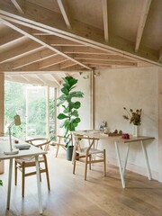 Bright and airy dining room interior with wooden furniture large fiddle leaf fig plant and natural sunlight streaming inside © Rubel