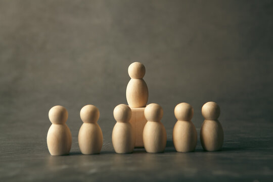 Business concept. Wooden figures of people stand in a row on a gray background.