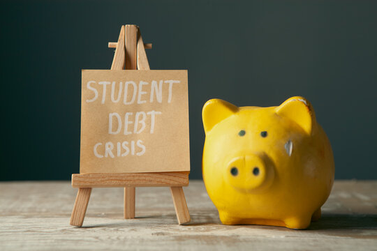 Piggy bank and sign with text STUDENT DEBT CRISIS