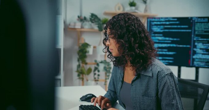Young black female developer wear glasses writes complex software code at desk in office. Artificial intelligence machine learning, Secure computer network, Advanced cloud data analysis trend concept.
