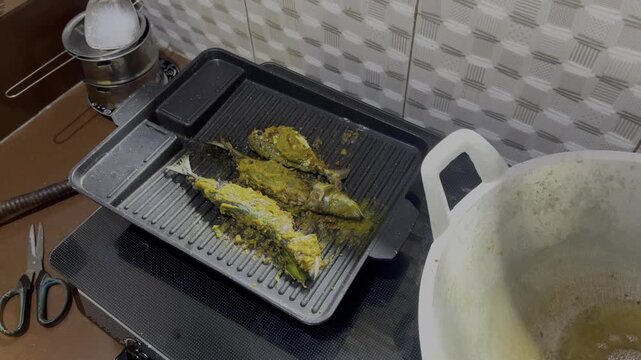 Hand flips fish on grill with tongs