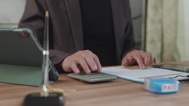 Accountant conducts financial accounting analysis at wooden desk, manages budget accounting tasks, handles invoice calculation paperwork.