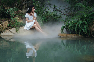 A princess or fairy in a mystical garden by the lake surrounded by trees and fog. © Anastasia