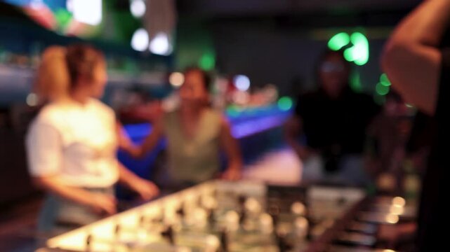 Blurred motion of young women enjoying lively game of foosball, having fun with friends in vibrant setting.
