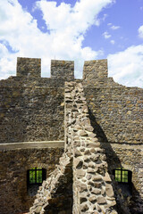Stone walls of a castle under a blue sky with white clouds. © Nick