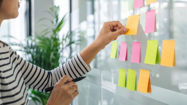 Person Placing Colorful Sticky Notes On A Glass Wall For Planning Ideas Project Management Strategy Development
