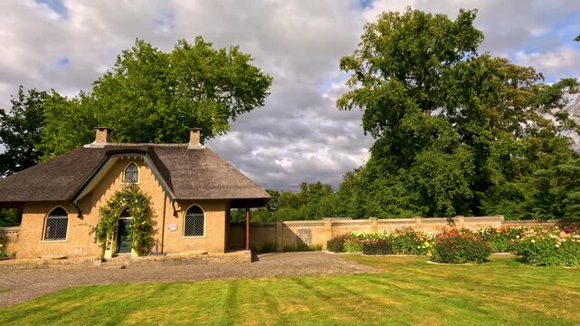 Charming thatched cottage with blooming flower garden and manicured lawn.