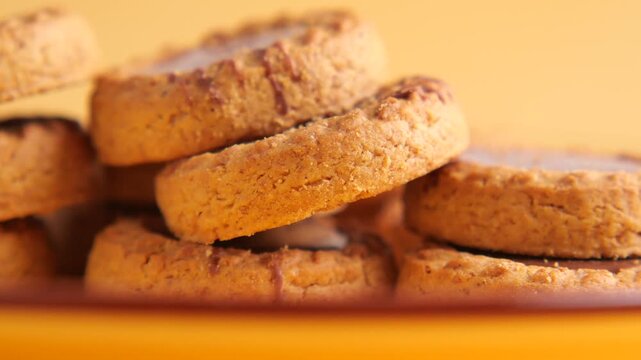 Macro slow motion shot of chocolate dipped oat cookies stacked on plate with smooth camera movement