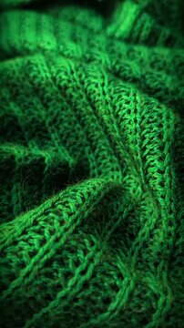 Close up cinematic pan video of green knitted wool fabric texture. Soft emerald sweater weave pattern background for winter and Christmas projects in candid style.